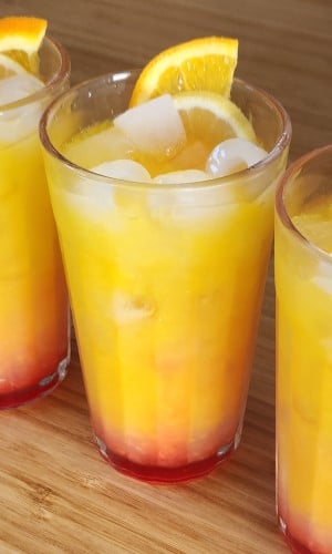Limoncello Sunrise cocktail in a tall tumbler with ice and a slice!
